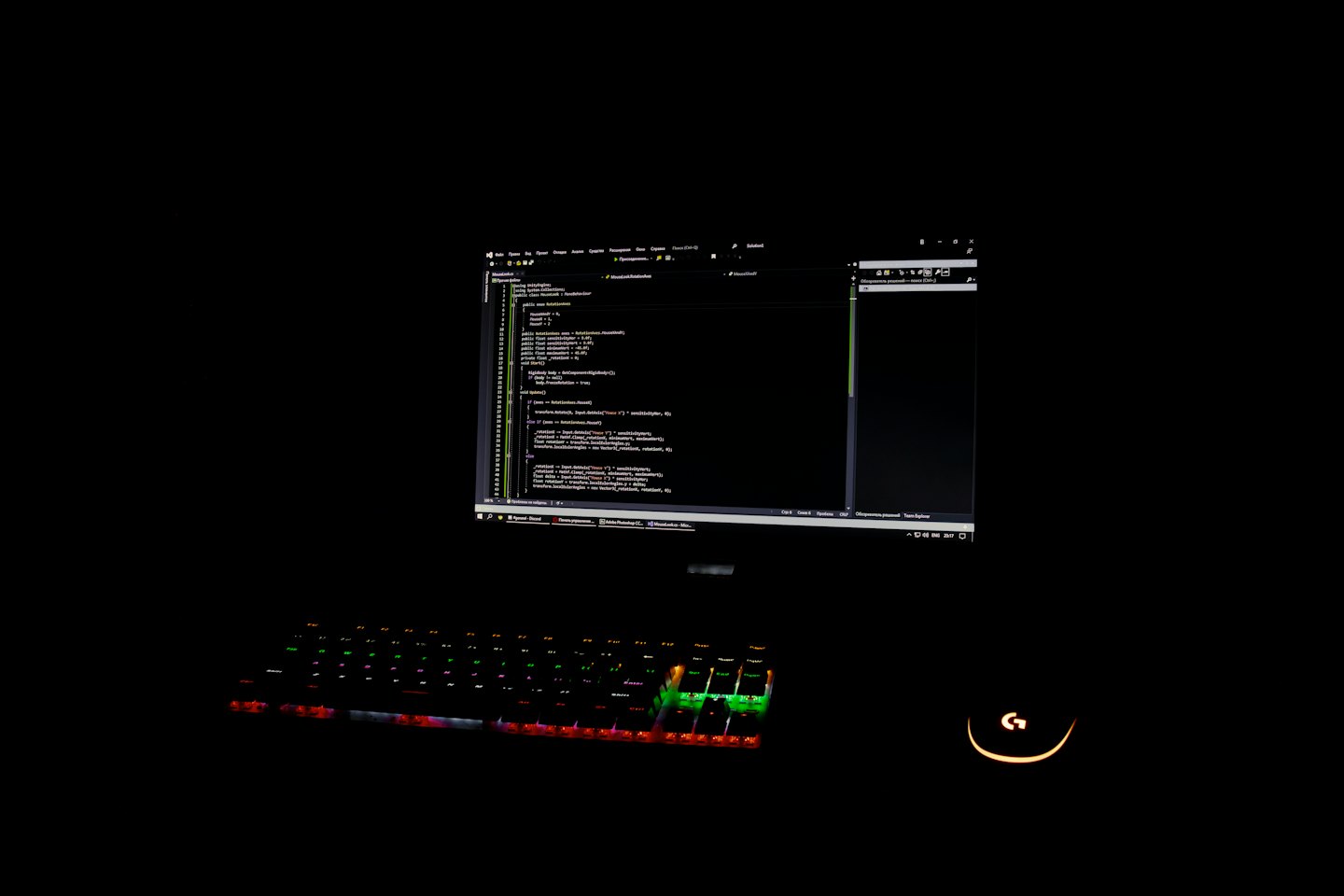 A computer monitor displays C# code above a glowing keyboard.